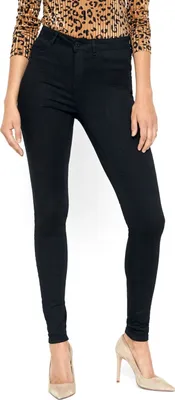 A person wearing black skinny jeans and beige high heels, shown from the waist down.