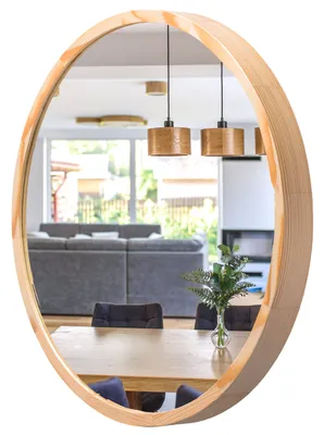 A round mirror with a wooden frame reflects a dining area and living room.