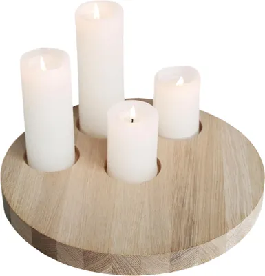 Four white pillar candles are lit and placed in a round wooden candle holder.