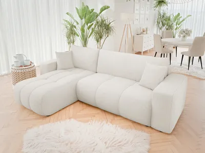 A modern living room with a white sectional sofa, plants, and dining area.