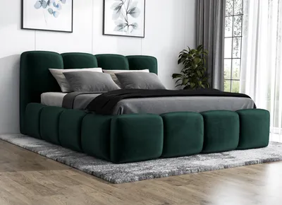 A green upholstered bed with a headboard and footboard, set up in a bedroom with a rug underneath and artwork on the wall.