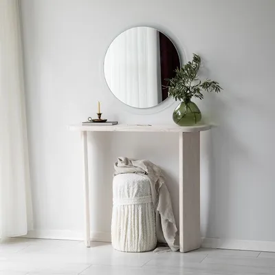 A minimalist entryway scene featuring a console table with a mirror, vase, and stool.