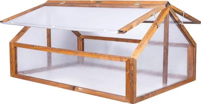 A wooden cold frame with a clear plastic lid, shown outdoors.