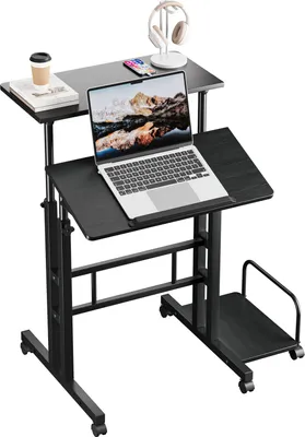 A black adjustable standing desk with a laptop, books, and a coffee cup on it.