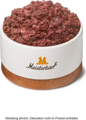 A bowl of raw dog food with a wooden base and a logo on the side.