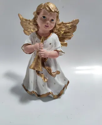 Eine Engelfigur, die eine Trompete hält. Mit goldenen Flügeln, weißen Kleid und einem goldenen Stern