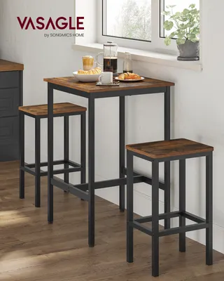 A small bar table and two stools are set up next to a window, with food and drinks on the table.