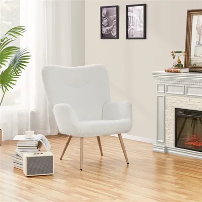 A white armchair in a living room setting next to a fireplace and a stack of books.