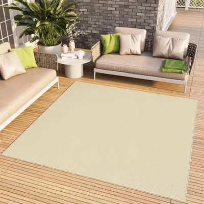 An outdoor patio setting with furniture and a rug.
