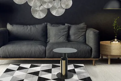A modern living room scene with a dark gray sofa, a geometric rug, and a stylish side table.