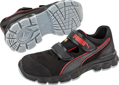 A pair of black Puma safety shoes with red accents and a gray sole are shown against a white background. One shoe is shown from the side, and the other is shown from the sole.