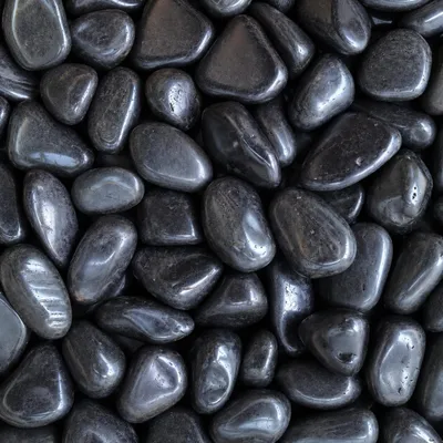 Schwarze Kieselsteine mit glänzender Oberflächenstruktur dicht nebeneinander im Detail