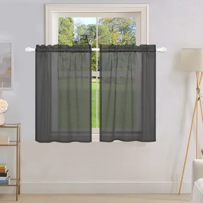 A window with dark gray sheer curtains hanging on a white rod.