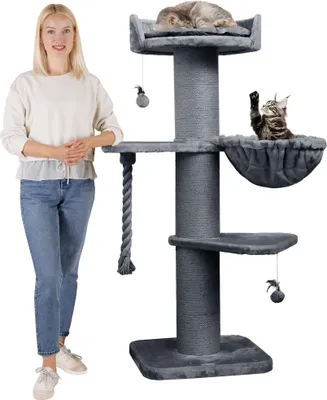 A woman stands next to a tall, multi-level cat tree with two cats on it.