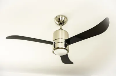 A modern ceiling fan with black blades and a brushed nickel finish is mounted on a white ceiling.