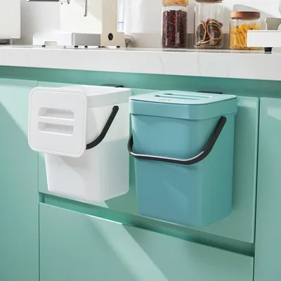 Two kitchen compost bins hanging on cabinet doors.