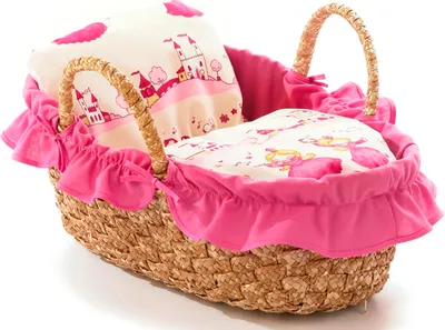 A doll's carry bag with a pink ruffled trim and a woven straw body, filled with bedding featuring a castle and princess print.