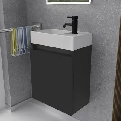 A modern bathroom vanity with a sink and faucet, featuring a dark gray cabinet and a white countertop. Towels are hanging on a rack to the left.