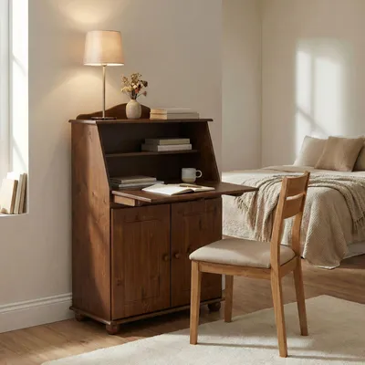 A wooden secretary desk with a chair in front of it, in a bedroom setting with a bed in the background.