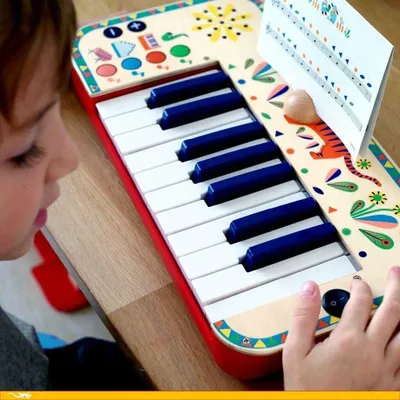 A child is playing with a colorful toy synthesizer.