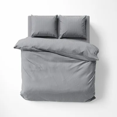 A top-down view of a gray striped duvet and two pillows on a bed.