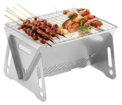 Silberner tragbarer Edelstahl-Grill mit verschiedenen Fleisch- und Gemüsespießen, die auf dem Rost braten