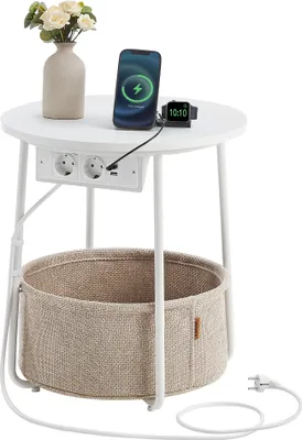 A round side table with integrated power outlets and USB ports, a woven storage basket underneath, and a phone and smartwatch charging on top.