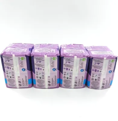 Four packages of Always Discreet Long sanitary pads are lined up against a white background.