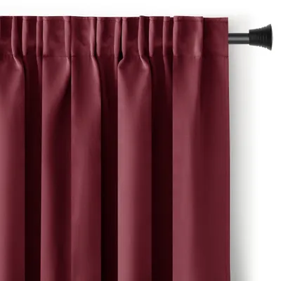 A close-up view of a burgundy blackout curtain hanging from a curtain rod.