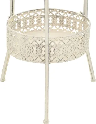 A close-up view of a white metal bistro table with a decorative, heart-patterned edge.
