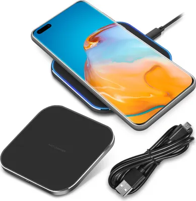 A black wireless charger with a smartphone on it, and a charging cable next to it.