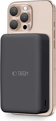 A dark gray power bank is attached to the back of a gold smartphone.