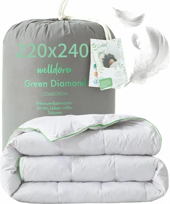 A folded duvet is shown in front of its grey fabric packaging bag, with feathers floating around.