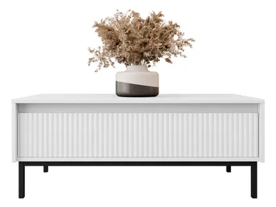 A white coffee table with a fluted drawer front and a vase of dried flowers on top, set against a white background.