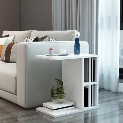 A white side table with shelves is placed next to a light-colored sofa in a living room setting.