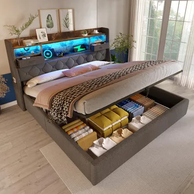 A modern upholstered bed with integrated storage and LED lighting, shown with the storage compartment open and filled with folded linens and clothing.