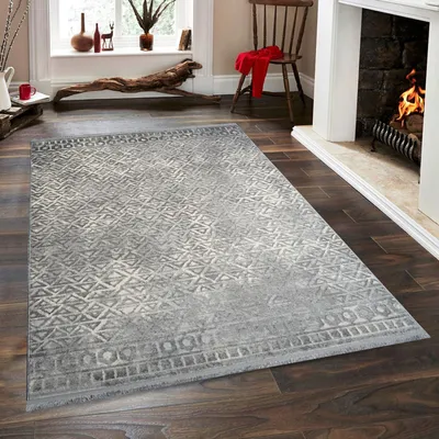 A rug is placed on a wooden floor in front of a fireplace.
