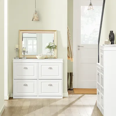 A hallway or entryway with a white shoe cabinet, a mirror, and a door.