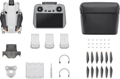 A flat lay of a drone and its accessories, including a remote controller, batteries, propellers, and a carrying case.