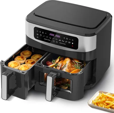 A dual-basket air fryer with food inside both baskets and a plate of french fries next to it.