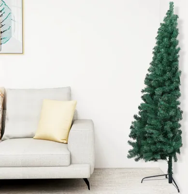 A green artificial Christmas tree with a stand is shown next to a sofa in a room.