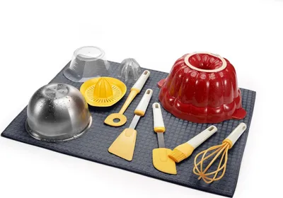 A collection of kitchen utensils and molds arranged on a dark textured mat.