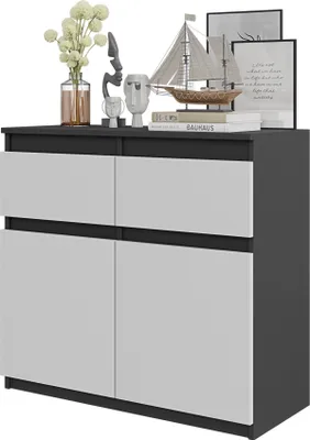 A modern dresser or sideboard with a dark gray frame and white drawers and doors. It is decorated with various items on top, including a vase with flowers, sculptures, and books.