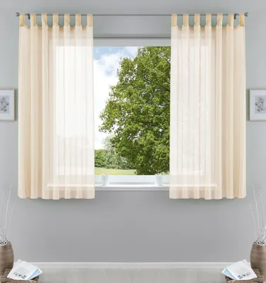 A window with cream-colored sheer curtains, showing a tree and sky outside.