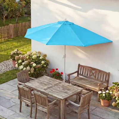 An outdoor patio scene with a table, chairs, and a half umbrella.