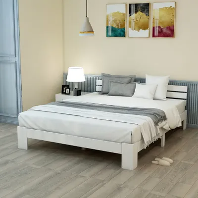 A bedroom scene with a white bed, nightstand, and artwork on the wall.