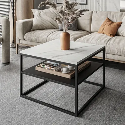 A modern living room scene featuring a square coffee table with a marble top and a lower shelf, placed on a gray carpet in front of a sofa.