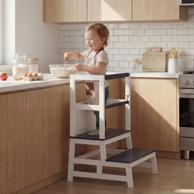 A child is using a learning tower in a kitchen.