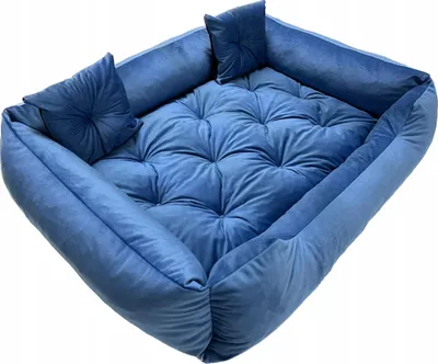 A blue pet bed with tufted cushioning and bolster sides, shown from a diagonal angle.