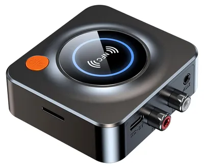 A close-up studio shot of a black wireless audio adapter with an orange button and a circular NFC indicator.